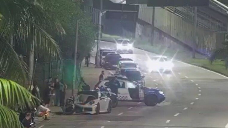 Porsche batido e carros da polícia na rua à noite