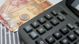 Notas de dinheiro, uma moeda e uma calculadora