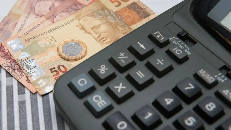 Notas de dinheiro, uma moeda e uma calculadora