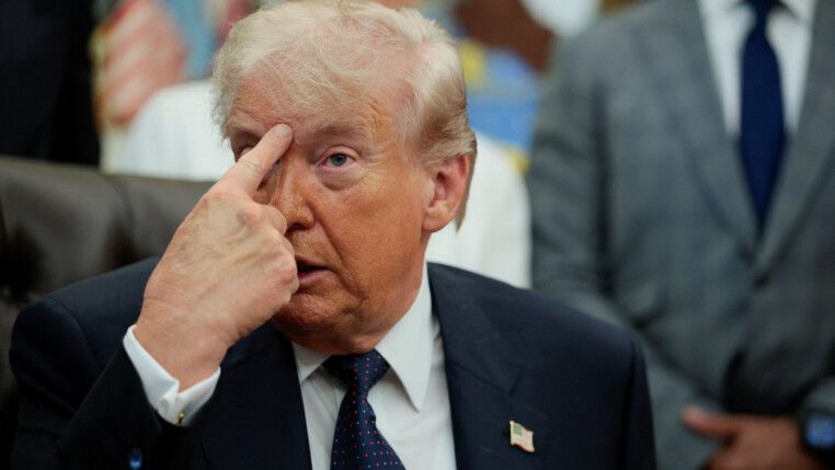 Trump aponta o dedo indicador para a sua própria testa