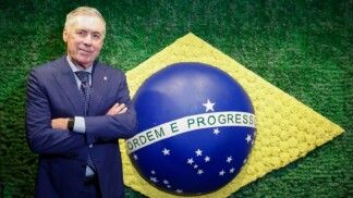 Ancelotti está de braços curados à frente da bandeira do Brasil