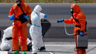 Pessoas usando equipamentos de proteção individual fazem preparativos na pista do aeroporto de Tenerife Sul, após a chegada do navio de cruzeiro MV Hondius, afetado por um surto de hantavírus, Ilhas Canárias, Espanha
