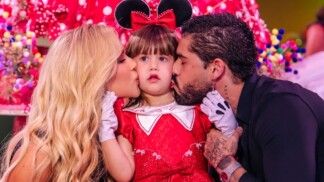 Virginia e Zé Felipe beijam simultaneamente as bochechas da filha Maria Alice, vestida de Minnie Mouse