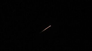 Um rastro de luz ilumina o céu durante um ataque de míssil do Irã em direção a Israel, visto de Jerusalém