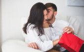 2147595981 Menino que beija sua namorada na bochecha, enquanto ela abre um saco vermelho