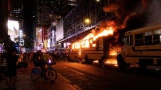 Revellers and fans celebrating the New York Knicks' win over the San Antonio Spurs and World Cup festivities watch as a city shuttle bus catches fire outside the Port Authority Bus Terminal in New York, U.S., June 14, 2026. The shuttles had been brought in to transport spectators to and from the New York/New Jersey stadium for the 2026 FIFA World Cup. REUTERS/Ed Ou TPX IMAGES OF THE DAY REFILE- ADDING COUNTRY NAME IN CAPTION