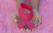 Mãos segurando um laço rosa, o símbolo universal da conscientização e prevenção do câncer de mama