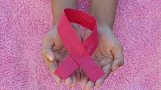 Mãos segurando um laço rosa, o símbolo universal da conscientização e prevenção do câncer de mama