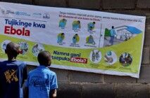 As crianças congolesas Ibrah Asimwe e Alex Uketi leem um cartaz informativo enquanto agências humanitárias intensificam os esforços para conter um novo surto de ebola causado pela variante Bundibugyo, em Bunia, na província de Ituri, na República Democrática do Congo
