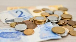 Notas de real e moedas espalhadas sobre mesa