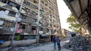 Moradores observam um prédio danificado em Catia La Mar, no estado de La Guaira, Venezuela, em 29/06/2026. As esperanças de encontrar sobreviventes diminuíam mais de quatro dias após os fortes terremotos que atingiram o país, enquanto aumentava a frustração da população com a resposta do governo ao desastre, que deixou ao menos 1.450 mortos e dezenas de milhares de desaparecidos.