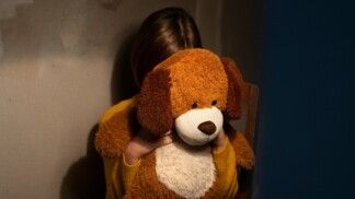 Menina escondendo o rosto com urso de pelúcia