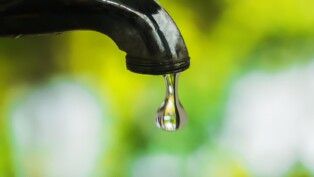 Foto de torneira pingando uma gota de água.