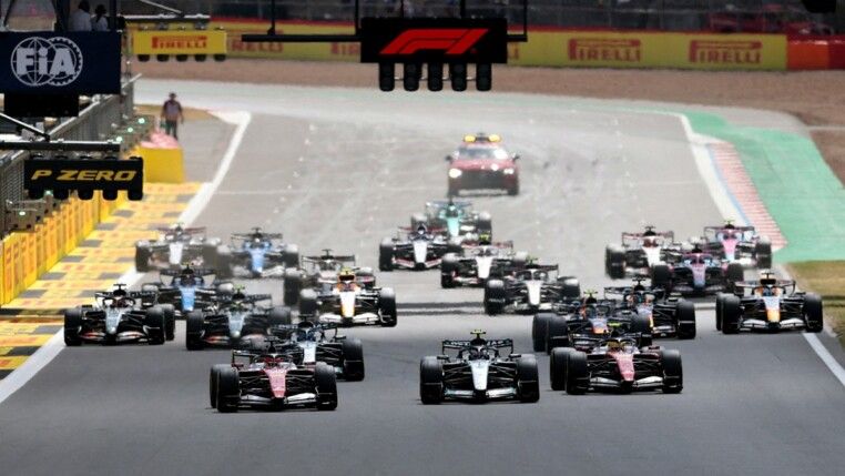Fórmula 1 — Grande Prêmio da Grã-Bretanha — Circuito de Silverstone, Silverstone, Reino Unido — 05/07/2026. Charles Leclerc, da Ferrari, lidera a primeira curva na largada da corrida, à frente do companheiro de equipe Lewis Hamilton e de Andrea Kimi Antonelli, da Mercedes.
