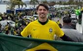 Jair Renan com a camisa da Seleção em carro elétrico, segurando a bandeira do Brasil