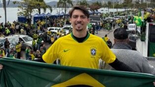 Jair Renan com a camisa da Seleção em carro elétrico, segurando a bandeira do Brasil