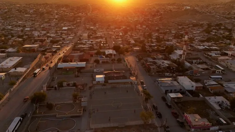 Imagem aérea mostra o campo de futebol onde Idaly Juache costumava jogar. Seus restos mortais foram encontrados dois anos após seu desaparecimento, em 2010, no Vale de Juárez. O registro foi feito em Ciudad Juárez, México, em 22/06/2026, enquanto o governo afirma que apoiar as "madres buscadoras" (mães que procuram familiares desaparecidos) é prioridade, mas parentes de desaparecidos denunciam burocracia, falta de apoio financeiro e a necessidade de realizar buscas por conta própria em áreas controladas por cartéis.